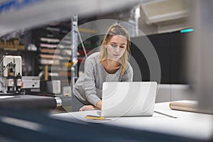 Woman using laptop at printing factory 